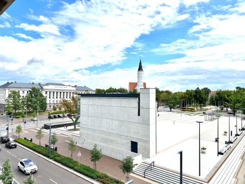 希奥利艾Butas pačiame Šiaulių miesto centre的一座白色的大建筑,在城市里有一个钟楼