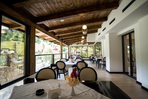 Statjunea BorsaHotel Roman Maramures - Ski & Spa Resort的餐厅设有桌椅和大窗户。