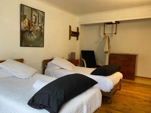 圣地亚哥El Pillan "Travelers" House的一间卧室设有三张床,墙上挂着一幅画