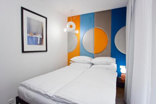 维斯瓦Willowa NO. 5 APARTAMENTS的一间卧室配有一张带白色床单和色彩缤纷墙壁的床。