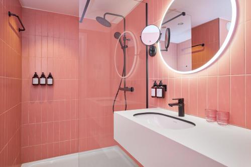 奥斯坦德Rosa Hotel的粉红色的浴室设有水槽和镜子