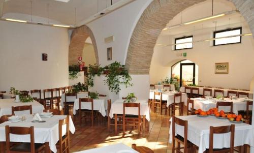 洛雷托Hotel Madonna di Loreto的一间设有白色桌椅的用餐室
