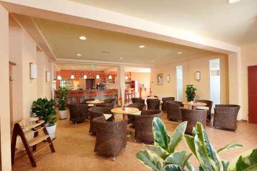 圣迈克尔隆高JUFA Hotel St Michael im Lungau的一间设有桌椅的餐厅,种植了植物