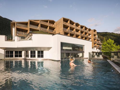 瓦勒斯法肯斯特诺温泉酒店的一名女子和一名儿童在酒店的游泳池里