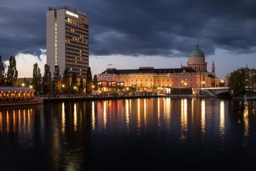 波茨坦波茨坦美居酒店的一座城市,在晚上有楼房和河流