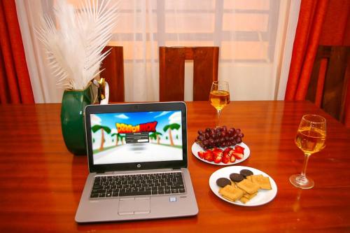 尼耶利Jaymorgan' cabins的一张坐在木桌旁的笔记本电脑,上面摆放着食物和葡萄酒
