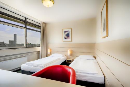 柏林Enjoy Hotel am Studio的一间医院间,配有两张床和红色椅子