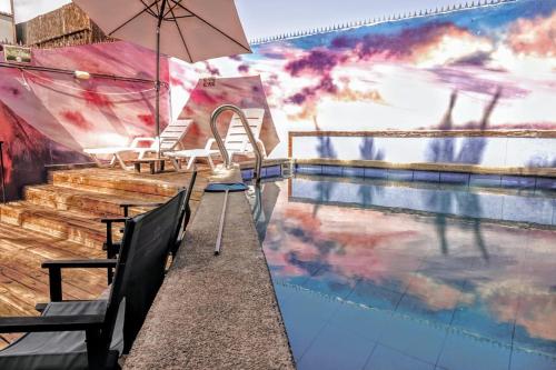 伊基克Aotea Hostel Iquique的一个带椅子和遮阳伞的游泳池,旁边是一张桌子