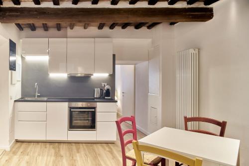 锡耶纳Casa Monelli的厨房配有白色橱柜和桌椅