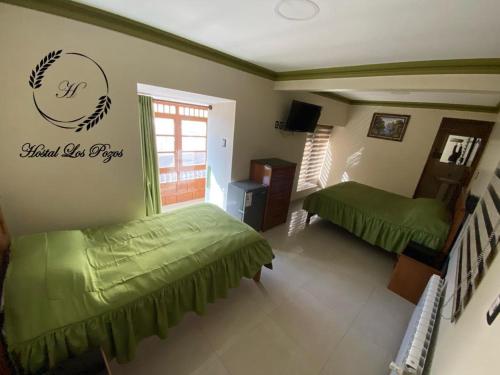 波托西Hostal Los Pozos的卧室配有两张床,墙上有标志