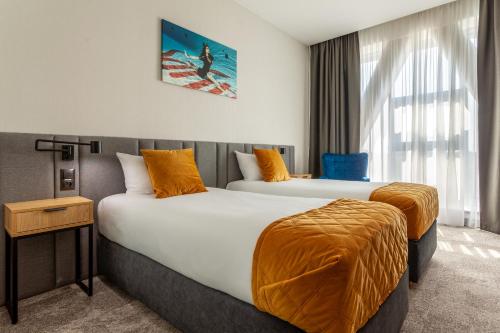 华沙Hotel Sante的酒店客房带两张带橙色床单的床