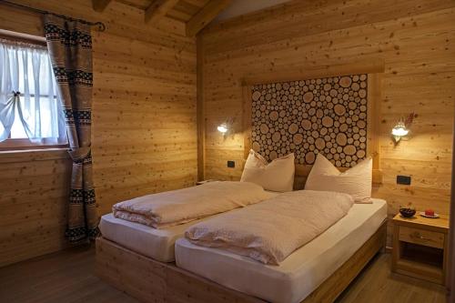 摩德纳迪-坎皮格里奥Chalet Camping Faè 2的木制客房内的一间卧室,配有一张床