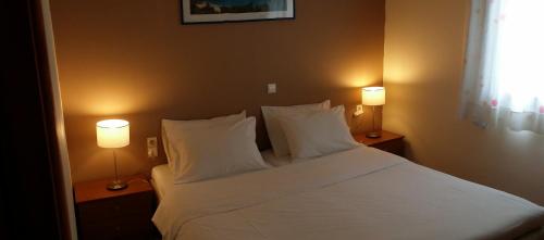 马塔拉谷村旅馆的一间卧室配有一张带两盏灯的大型白色床。