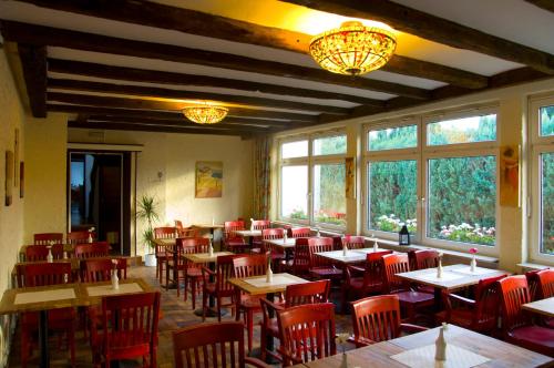 贝尔吉施格拉德巴赫瑞法拉舍科隆酒店的餐厅设有桌子和红色椅子以及窗户。