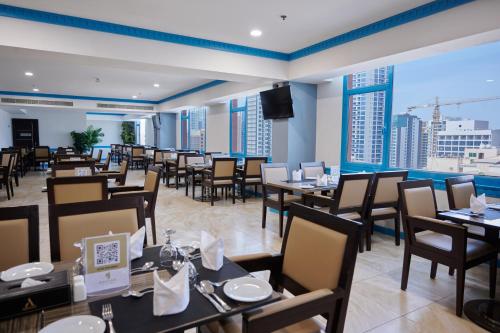 麦纳麦Arman Hotel Juffair Mall的餐厅设有桌椅和大窗户。