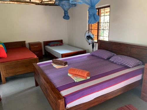 ButtalaSahana Retreat的一间卧室配有一张带紫色床单的床和窗户。