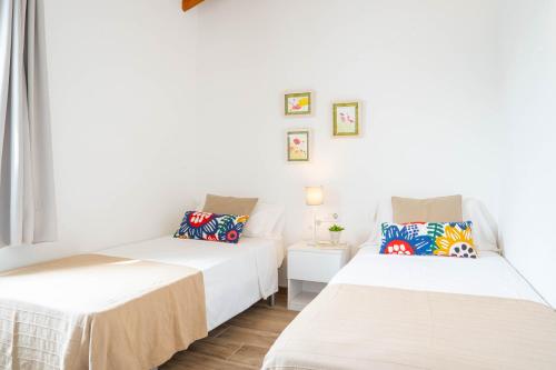 卡兰博希Apartamento Calan Bosch, Ciutadella的白色墙壁客房的两张床