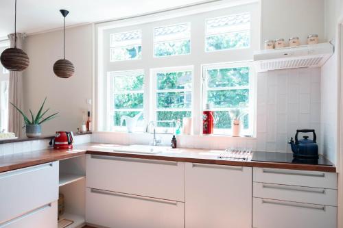 埃丹Bed and breakfast Jan的白色的厨房配有白色橱柜和窗户。