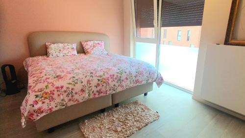 安特卫普Mooi vakantiehuis tussen Breda, Antwerpen, Gent & Hasselt的一间卧室配有一张带粉红色棉被的床和窗户