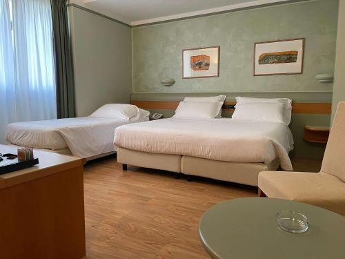 埃尔巴Best Western Hotel Leonardo da Vinci的酒店客房,设有两张床和一张沙发
