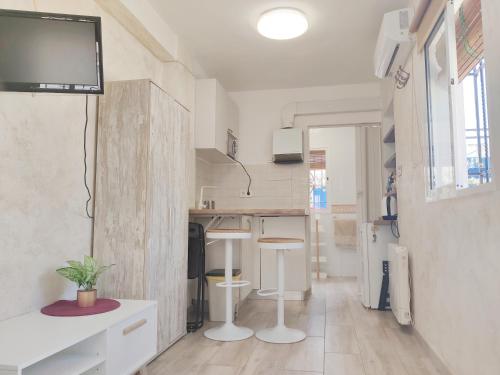 格拉纳达Lolas Cozy Studio的小厨房配有白色的柜台,墙上配有电视