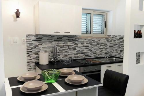 拉茨斯切Family friendly apartments with a swimming pool Kneza, Korcula - 9130的厨房配有带盘子的桌子