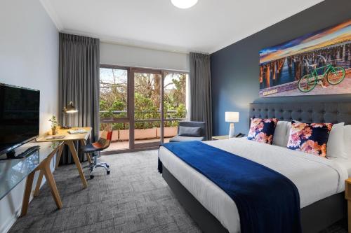 墨尔本Kimberley Gardens Hotel, Serviced Apartments and Serviced Villas的酒店客房配有一张床、一张书桌和一台电视。