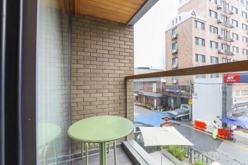 釜山Brown Dot Hotel Haeundae的阳台设有绿桌和窗户。
