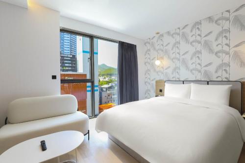 釜山Brown Dot Hotel Haeundae的白色的卧室配有白色的床和沙发