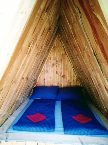 LenzingCamping Dreieck的帐篷内的一张床位,上面有两个红色枕头