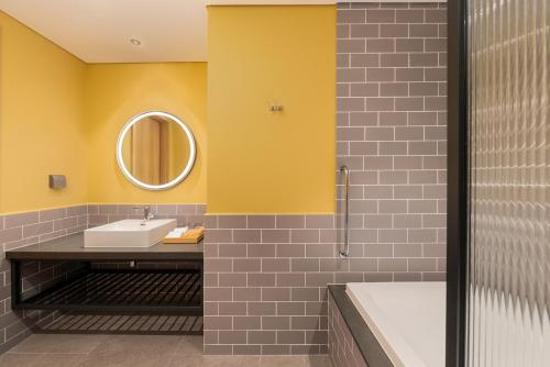 顺安HIIVE by Fusion Binh Duong的一间带水槽、浴缸和镜子的浴室