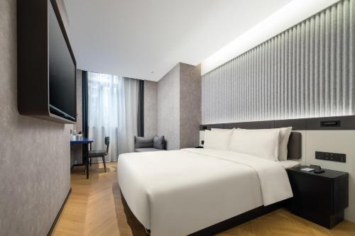 上海上海闵行马桥轻居酒店的卧室配有一张白色大床和电视。