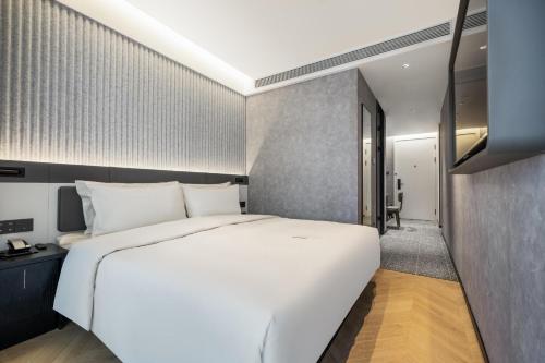 上海上海闵行马桥轻居酒店的卧室设有一张白色大床和一个走廊