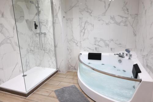 蒙斯Capsule 90's - Jacuzzi - Sauna - Flipper - Billard - Netflix - Nintendo Switch & Jeux -的白色的浴室设有浴缸和淋浴。