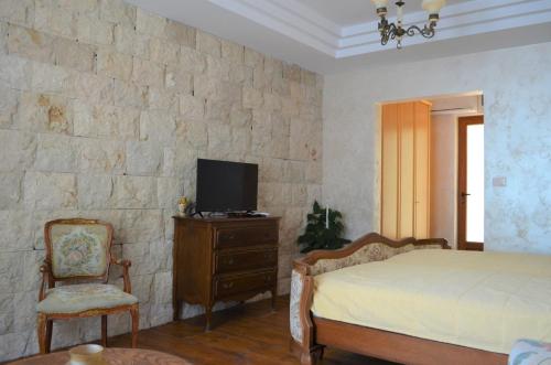 采蒂涅Markovic Winery and Estate apartments的一间卧室设有一张床,石墙上配有电视。