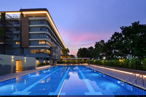 巴吞他尼Tinidee Hotel Bangkok Golf Club - SHA Certified的一座游泳池,在晚上在建筑物前