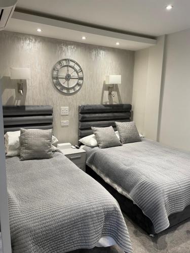 伦敦公园大道酒店 的一间卧室设有两张床,墙上挂着一个时钟。