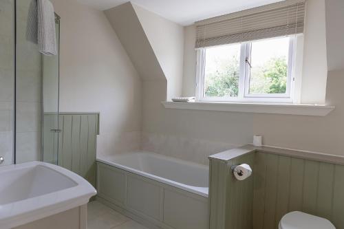 格伦科Duart Cottage的带浴缸的浴室和窗户。