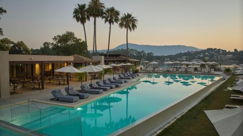 古维亚Dreams Corfu Resort & Spa - All Inclusive的一个带躺椅和遮阳伞的大型游泳池