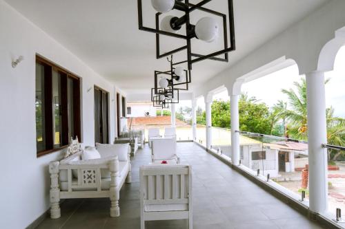 马林迪Met Beach Resort Malindi的白色门廊,配有白色椅子和吊灯