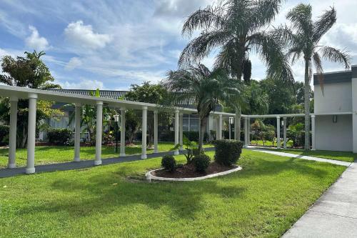 可可Ramada by Wyndham Cocoa的庭院里棕榈树的白色凉亭