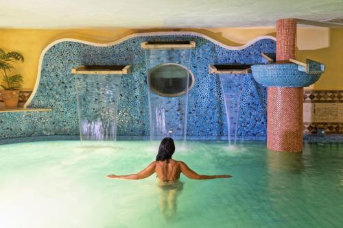 伊斯基亚Hotel Terme Tritone Resort & Spa的喷泉游泳池里的女人