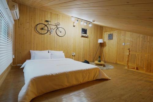 顺天市Suncheon Bay Healing Pension的卧室配有一张床,墙上挂着自行车