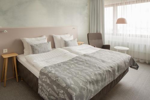赫尔辛基所库斯赫尔辛基总统酒店的一间卧室配有一张大床和一把椅子