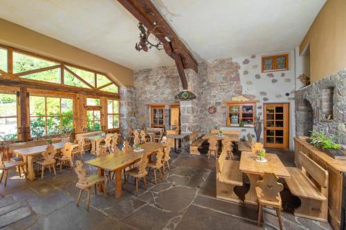 博尔扎诺Steidlerhof的一间设有木桌和椅子的餐厅以及石墙