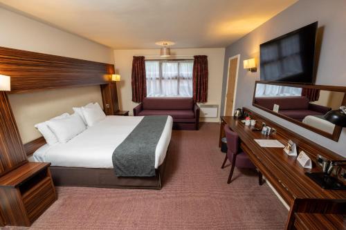 布莱克本The Fernhurst by Greene King Inns的配有一张床和一张书桌的酒店客房