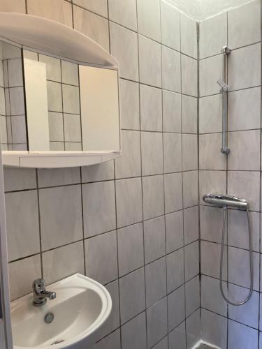 帕兹堡Padborg Hotel的白色瓷砖浴室设有水槽和淋浴