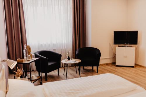 KollmarFährhaus Kollmar的酒店客房设有两把椅子、一张桌子和电视。