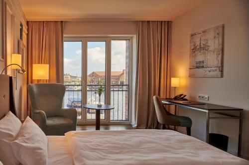 埃姆登Hotel am Delft的配有一张床、一张书桌和一扇窗户的酒店客房