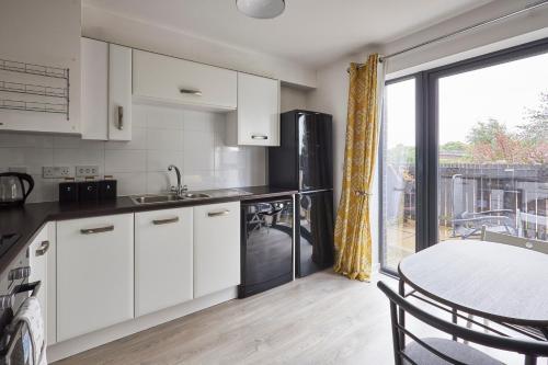 格拉斯哥Host & Stay - London Avenue的厨房配有白色橱柜、桌子和窗户。